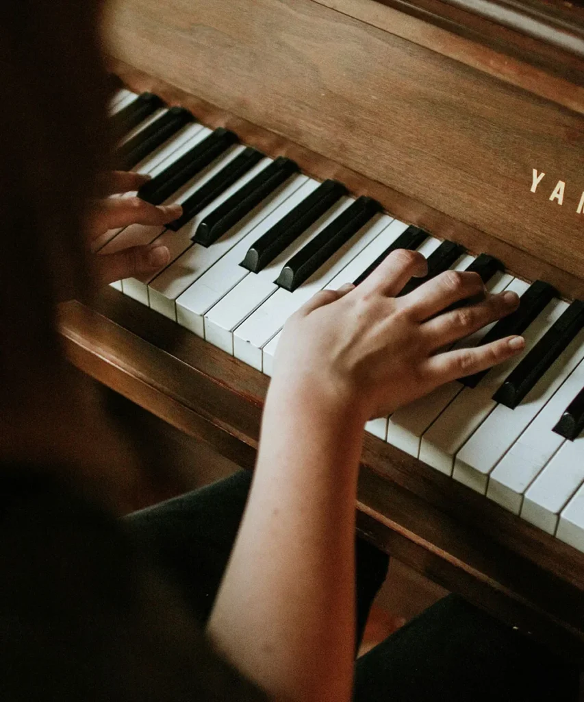 Hands playing an upright piano